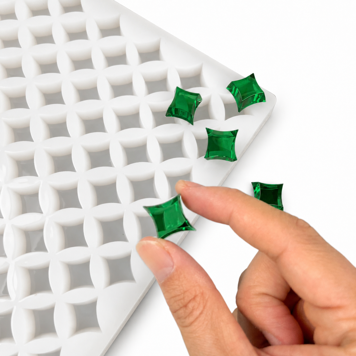 Hand pressing a finished emerald green star gummy in a flexible silicone gummy mold